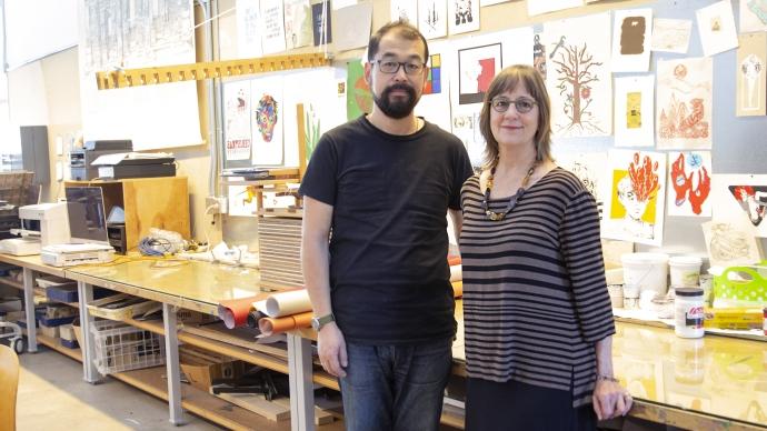 Ward Lee standing with other person in front of their art pieces in a gallery. 