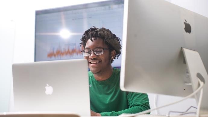 Smiling student looks at laptop