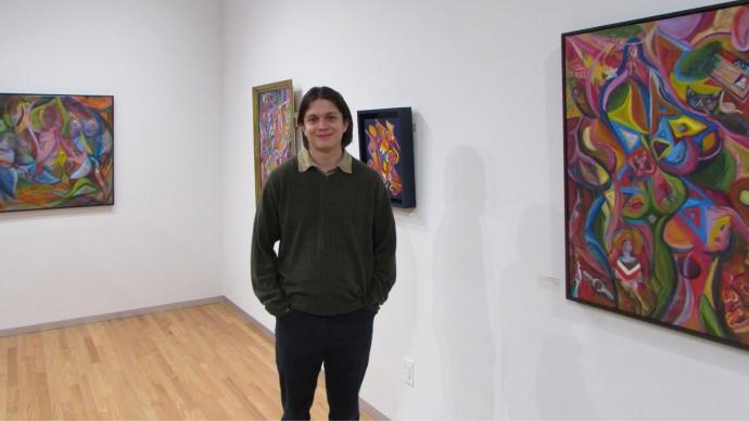 Pedro Acosta stands in gallery displaying his art