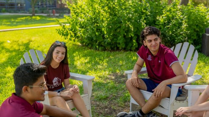 学生 wearing 赌博娱乐平台网址大全 shirts sit in Adirondack chair and chat outside