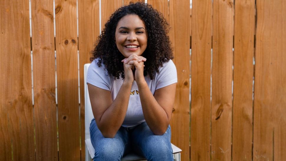 Caelia Marshall sits in front of fence