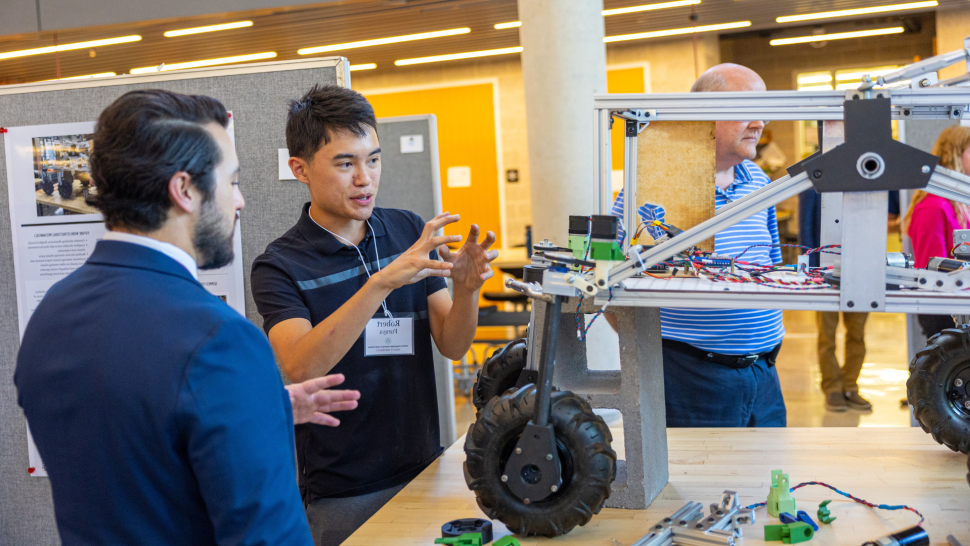 A student explains his engineering project to someone at the Summer Undergraduate Rsearch 和 Internship Symposium