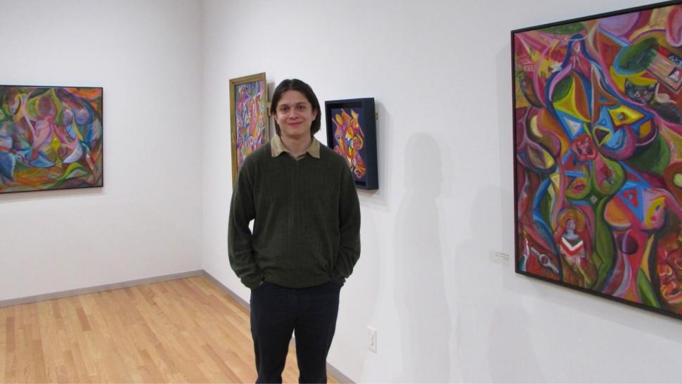 Pedro Acosta stands in gallery displaying his art