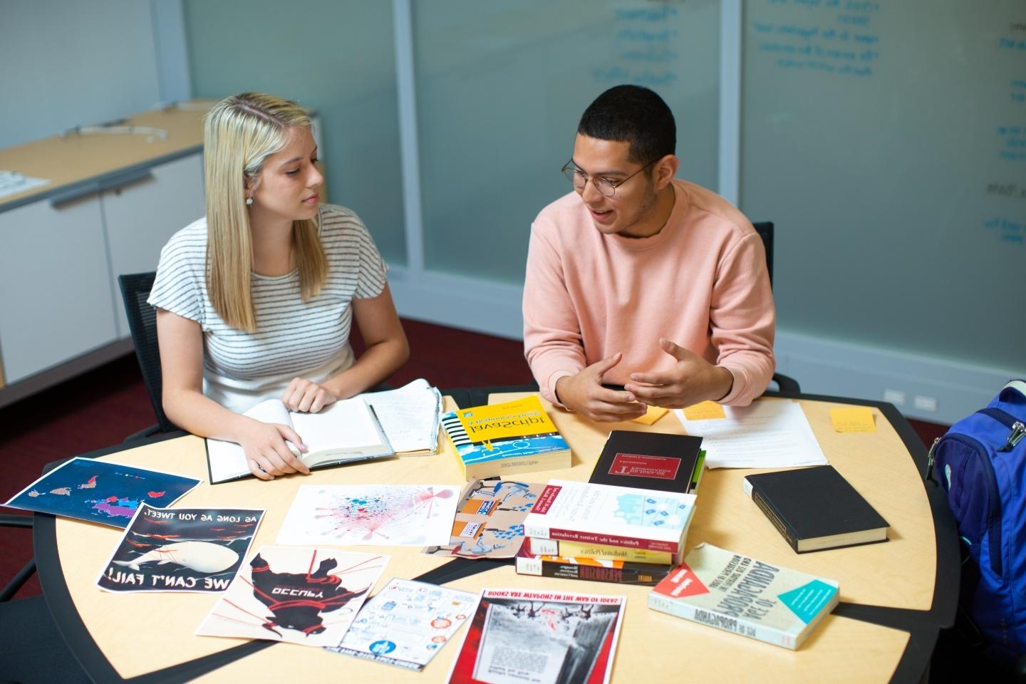 Students around a table with books and work projects