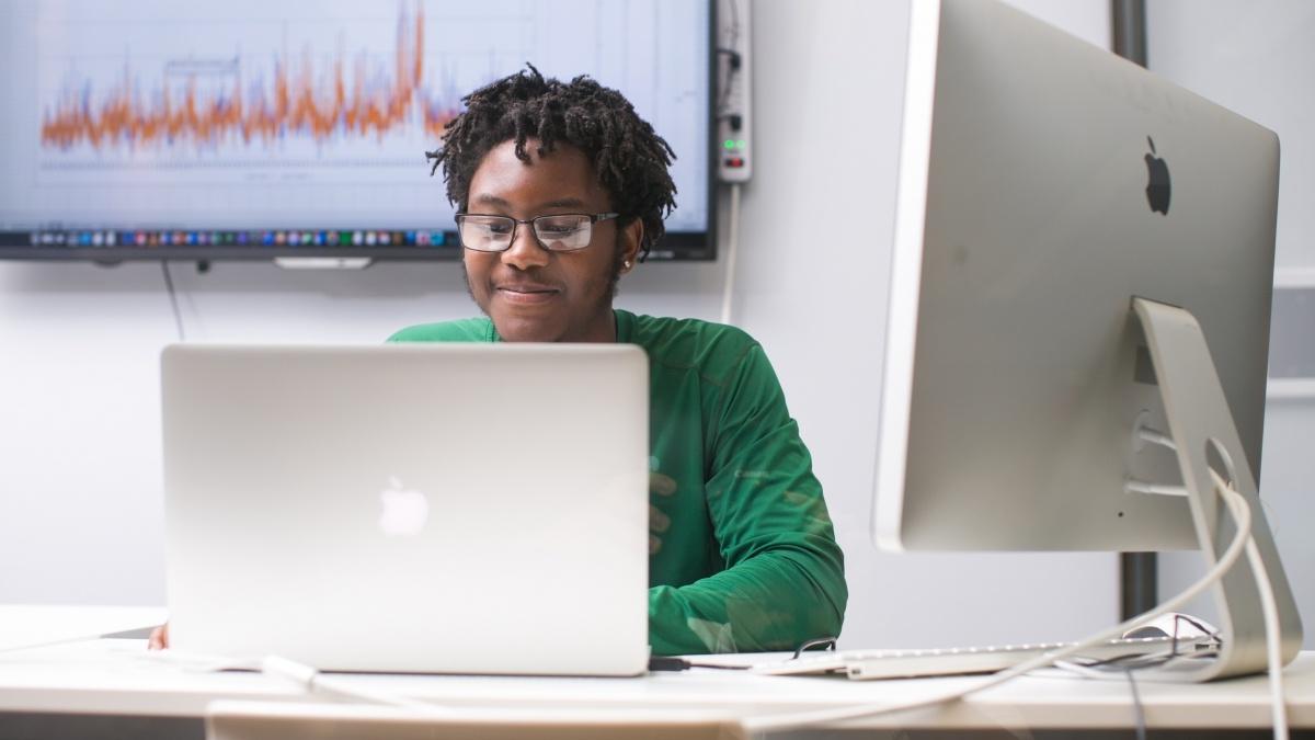 Student working on computer with two monitors