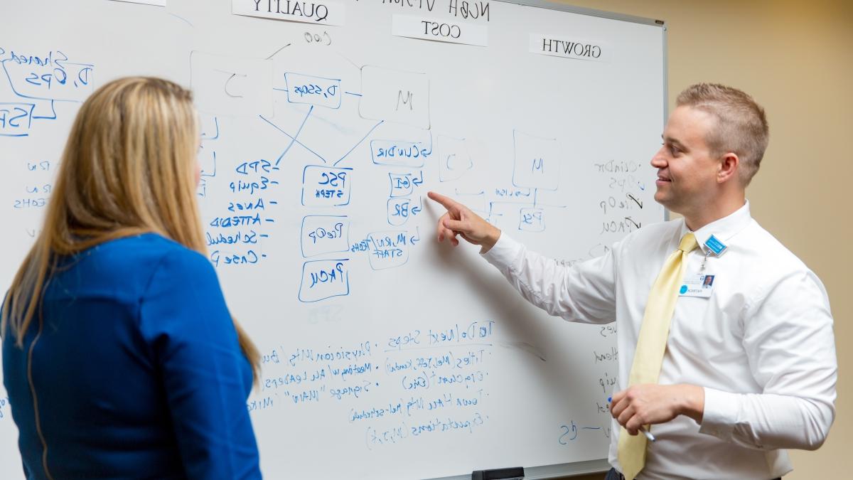 校友 Patrick Halinsky uses a white board to map a process at a local hospital.